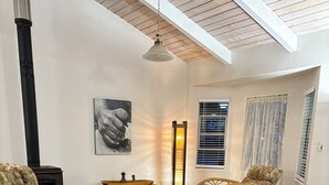 Ein gemütliches Zimmer mit einem Bett, zwei Korbstühlen, einem kleinen Tisch, einer Stehlampe und einem Kamin.