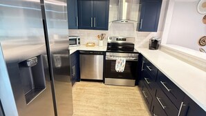 Una cocina moderna con armarios oscuros, electrodomésticos de acero inoxidable y techo de madera.