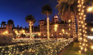 A historic building with a formal garden, illuminated by string lights, and palm trees. - Across from St Augustine Beach-Sunny Stylish stay steps from the Shore & Fun (St. Augustine)