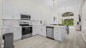 Een moderne keuken met witte kasten, roestvrijstalen apparatuur en een centraal eiland.