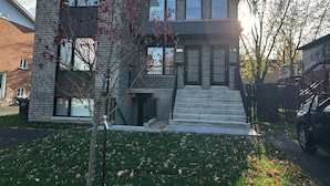 Une maison moderne à deux étages, avec une façade en briques, de grandes fenêtres et un numéro de maison bien visible.