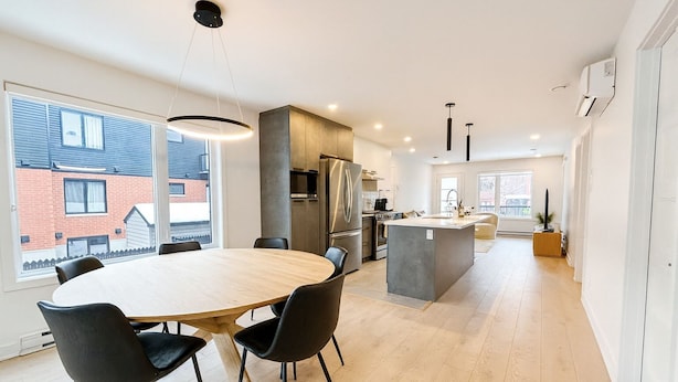 Une cuisine moderne avec un îlot central, des chaises noires et une grande table à manger.