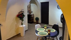 A dining area with a table set for two, a potted plant, and a dartboard on the wall.