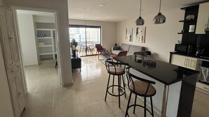 Une cuisine moderne dotée d’un îlot central, de tabourets de bar et de luminaires suspendus.