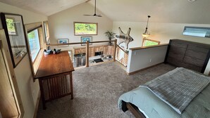 Ein Schlafzimmer im Loft-Stil mit einem großen Bett, einem Holztisch und Blick in den Hinterhof durch ein Fenster.