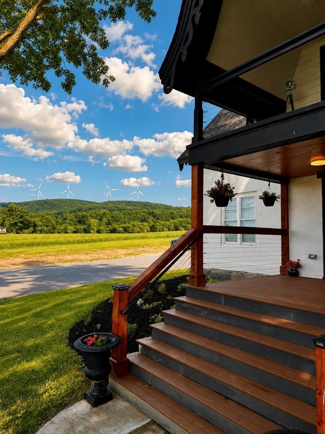 A building with a wooden staircase leading to a porch with hanging flower baskets.