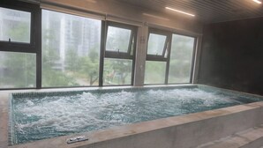 A hot tub with a view of trees through large windows.