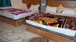 Een hotelkamer met twee bedden, elk met een ander beddegoed. De kamer heeft een houten hoofdbord en een marmeren vloer.