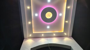 Een moderne, verlichte wand met een centraal rond ontwerp en omliggende vierkante lampen.