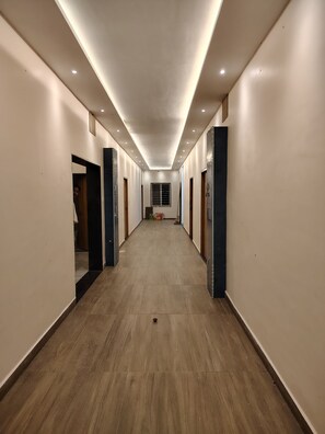 A long, narrow hallway with wooden flooring and white walls.
