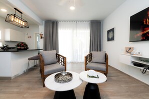 Ein modernes Wohnzimmer mit zwei grauen Sesseln, einem weißen Couchtisch und einer Küche im Hintergrund.