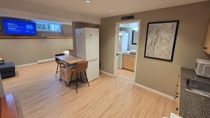 A modern kitchen with a wooden countertop, a refrigerator, and a microwave. There is a small dining area with a table and chairs. - Amazingly convenient central location in Rossland with everything you need! (Rossland)