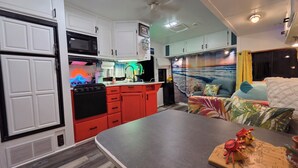 A compact kitchen with white cabinets, a red stove, and a microwave.