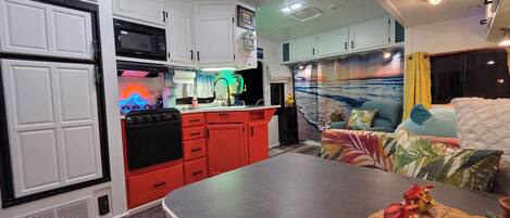 A compact kitchen with white cabinets, a red stove, and a microwave.
