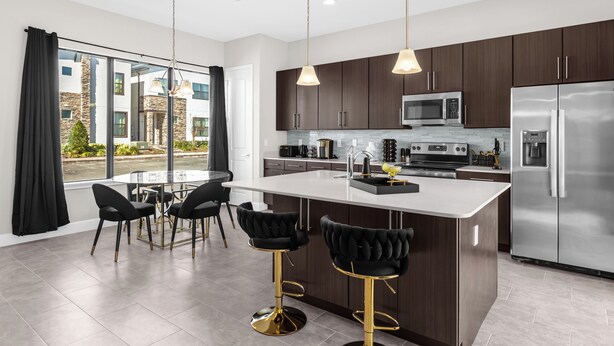 Una cucina moderna con pensili in legno scuro, elettrodomestici in acciaio inox e una grande isola con sgabelli da bar.