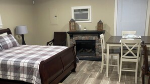 Une chambre à coucher comprenant un lit, une cheminée, une table à manger avec des chaises et une lampe.