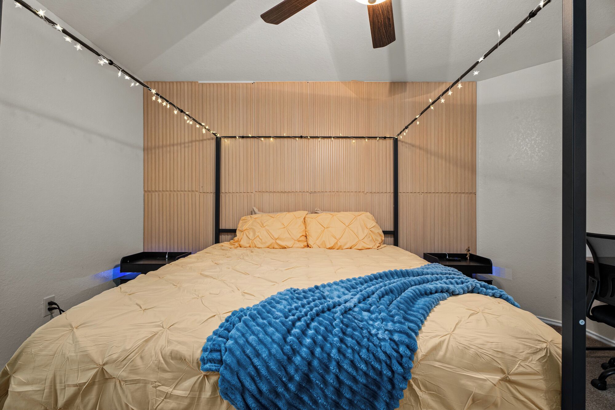 Een slaapkamer met een bed, een houten hoofdbord en lichtslingers.