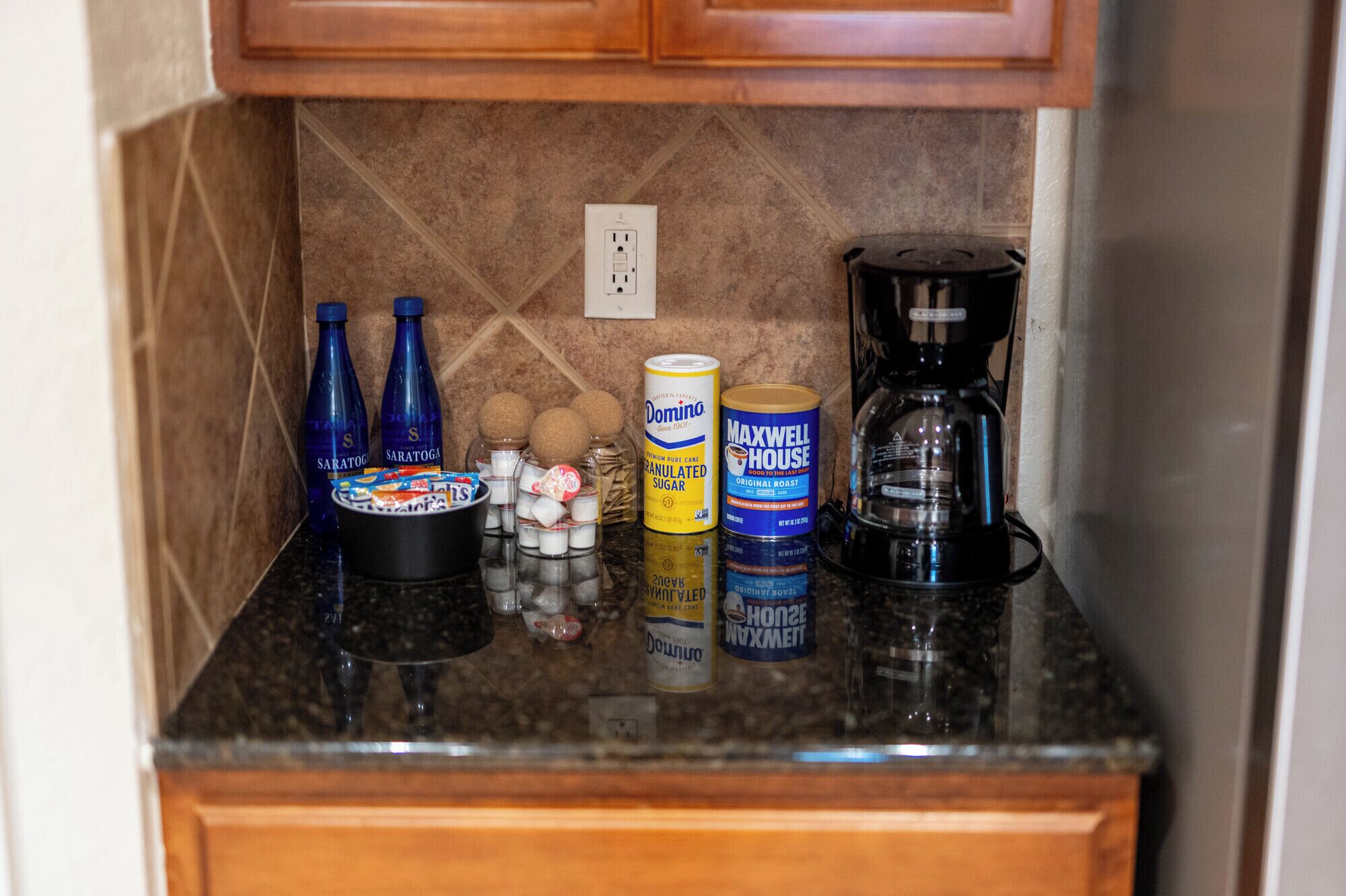 A kitchen counter with various items including bottles, a coffee maker, and canned goods.