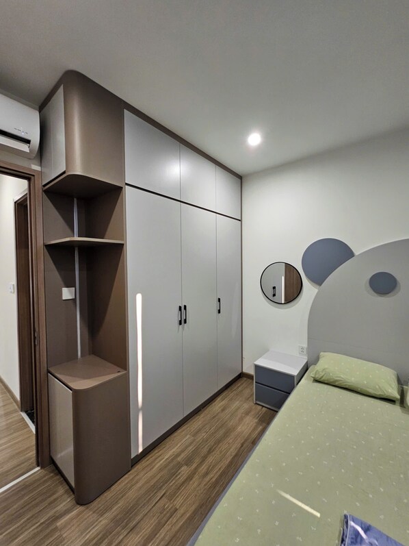 Ein Schlafzimmer mit einem Bett, einem Kleiderschrank, einem Spiegel und einem Nachttisch.