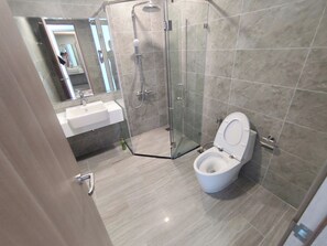 Ein modernes Badezimmer mit einer Glaskabine zur Dusche, einer weißen Toilette und einem Waschbecken.