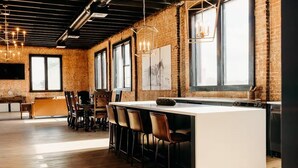 Una cocina moderna con una isla central, taburetes de bar y una pared de ladrillo.