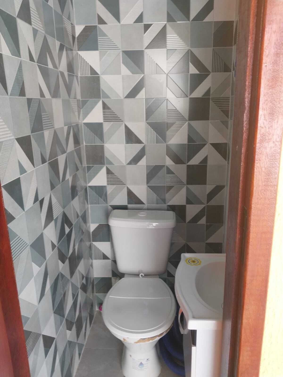 Une salle de bain avec un mur orné d’un motif géométrique, des toilettes blanches et un lavabo.
