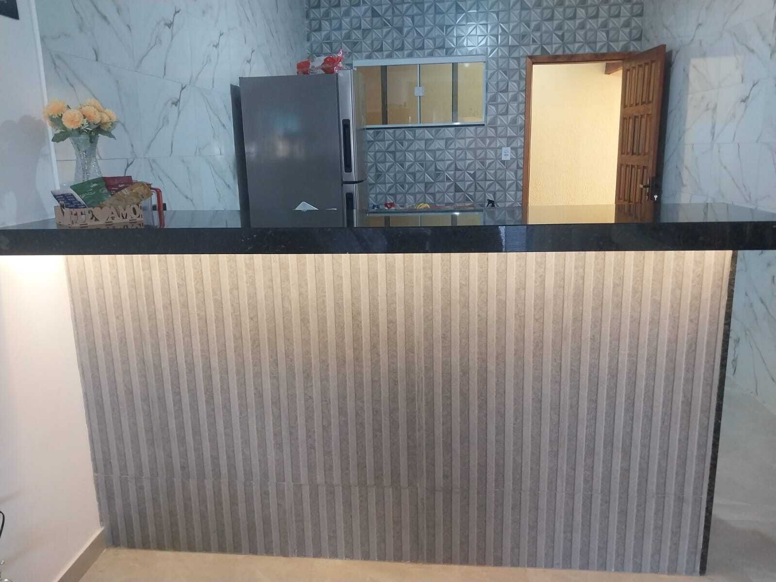 Eine Küche mit Marmorfliesen an der Spritzschutzwand, einem Kühlschrank und einer Holztür.