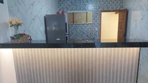 A kitchen with a marble backsplash, a refrigerator, and a wooden door. - Paradise Family House - your beach house! (Tamoios)