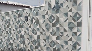 A swimming pool with a geometric tile wall and a door to the right. - Paradise Family House - your beach house! (Tamoios)