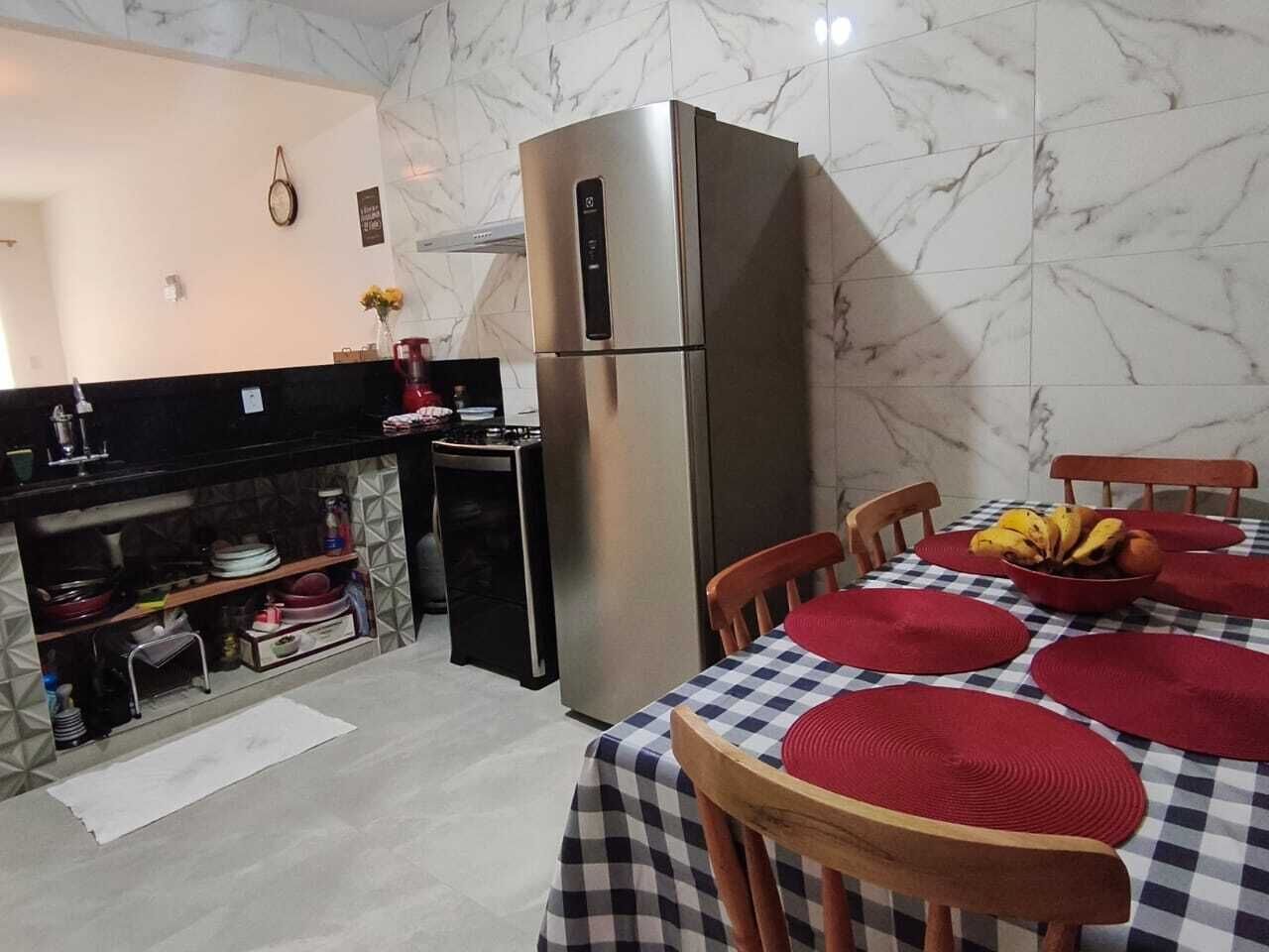 A compact kitchen with a refrigerator, a stove, and a dining area with a checkered tablecloth and red placemats.