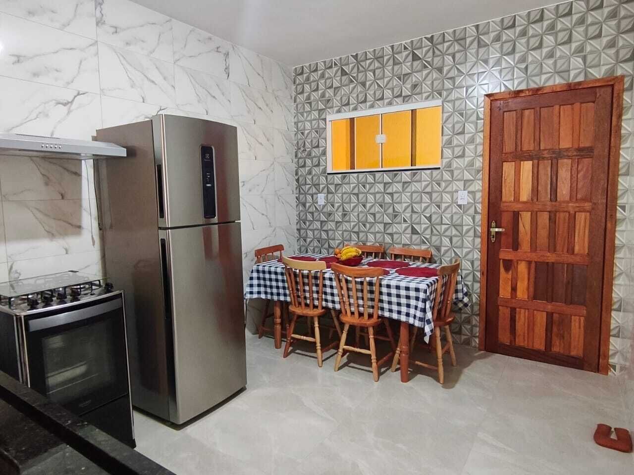 Una cocina equipada con refrigerador, estufa y una mesa de comedor con sillas.