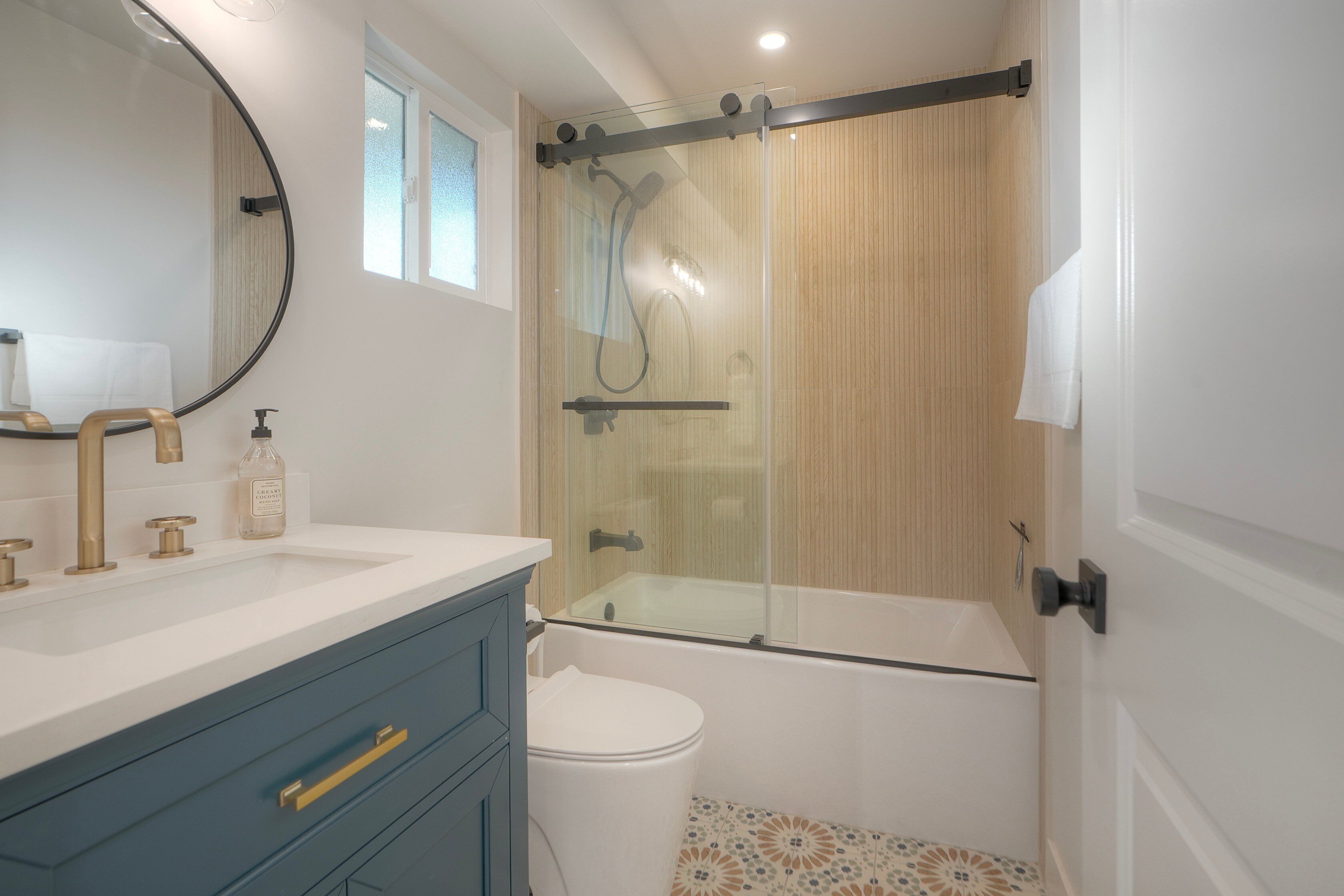 Une salle de bain avec une douche à parois de verre, des toilettes blanches et un meuble-lavabo doté d’un miroir et de deux vasques.