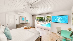 Ein Schlafzimmer mit Bett, Schreibtisch, Stuhl, Fernseher und Blick auf einen Außenpool.