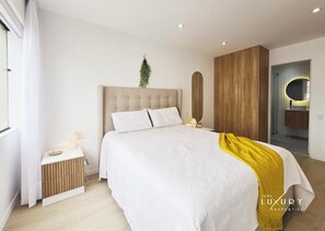 Een moderne slaapkamer met een groot bed, een nachtkastje met een lamp en een houten garderobe.