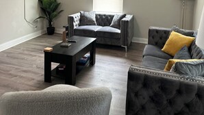 Ein Wohnzimmer mit grauem Sofa, Couchtisch, Fernseher und Deckenventilator.