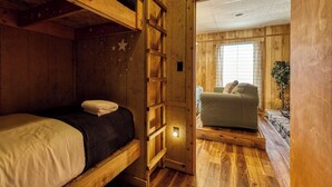 A wooden interior with bunk beds, a sofa, and a window. - Panoramic Views•Games•HotTub •Theater•Golf•3 Pools (Gatlinburg)