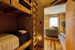 A wooden interior with bunk beds, a sofa, and a window. - Panoramic Views•Games•HotTub •Theater•Golf•3 Pools (Gatlinburg)