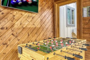 A foosball table in a room with wooden walls and a window. - Panoramic Views•Games•HotTub •Theater•Golf•3 Pools (Gatlinburg)