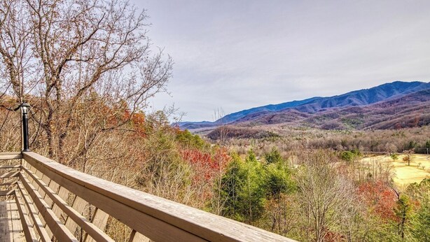 A wooden deck overlooking a mountainous landscape with autumn foliage. - Panoramic Views•Games•HotTub •Theater•Golf•3 Pools (Gatlinburg)