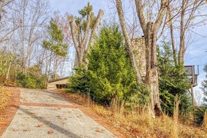A concrete pathway leading to a building with a brick base, surrounded by trees and shrubs. - Panoramic Views•Games•HotTub •Theater•Golf•3 Pools (Gatlinburg)