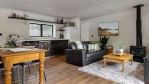 Eine moderne Küche mit Essbereich, einem schwarzen Ledersofa und einem Kamin.