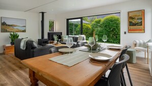 Ein modernes Wohnzimmer mit Essbereich, großen Fenstern und einem Kamin.