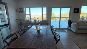 En matplats med ett träbord, stolar och utsikt över ett snötäckt landskap genom stora fönster.