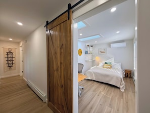 Une pièce dotée d’une porte coulissante de style grange, d’un lit avec une literie à rayures, d’un bureau et d’une chaise.