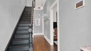 A staircase with black railings and wooden steps leading to a room with a television and shelves.