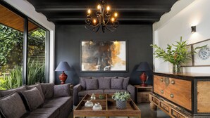 Un salon moderne avec un mur d’accent de couleur foncée, une grande peinture abstraite et une table basse en bois agrémentée d’objets décoratifs.
