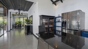 Une cuisine moderne dotée d’un grand réfrigérateur en acier inoxydable, d’un îlot central noir et d’un coin repas agrémenté d’un lustre.