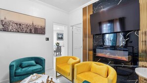 Ein modernes Wohnzimmer mit Türkis- und Gelbsofas, einem Kamin und einem Stadtbild als Gemälde an der Wand.