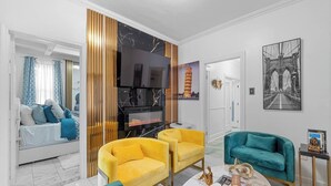 Ein modernes Wohnzimmer mit Kamin, gelben Sesseln, einem türkisfarbenen Sofa und einem Fernseher.
