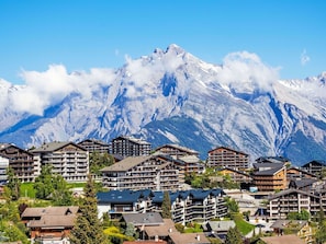 Une station de montagne avec des bâtiments à plusieurs étages, qui propose probablement des hébergements et diverses commodités, le tout situé au pied de sommets enneigés.